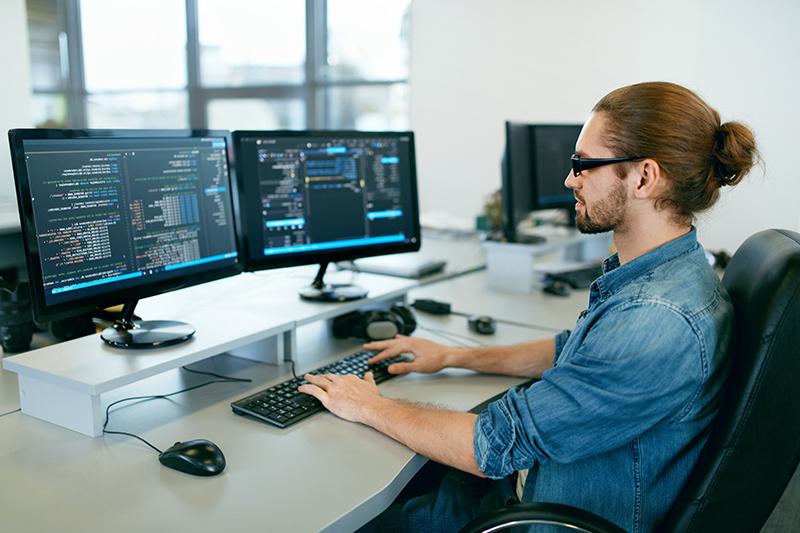 Programmation. 在电脑办公室用电脑工作的人, assis à son bureau, écrivant des codes. 程序员输入数据代码, 在软件开发公司从事一个项目. Image de haute qualité.
